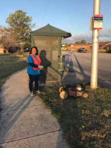 Lady mowing grass at bus stop